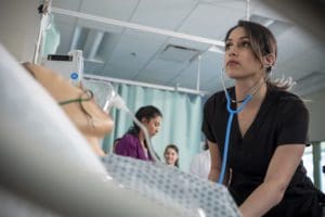 munika, lpn, rn, in the lab with a stethoscope, working on a high-fidelity mannequin