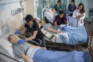 Munika and other students in the nursing lab, working on high-fidelity mannequins.