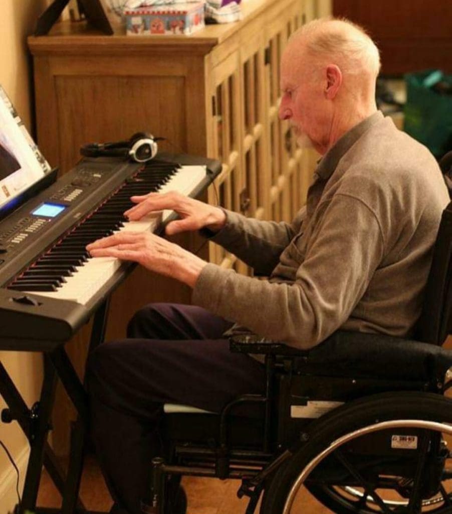 Natasha's dad playing the piano while sitting in a wheelchair