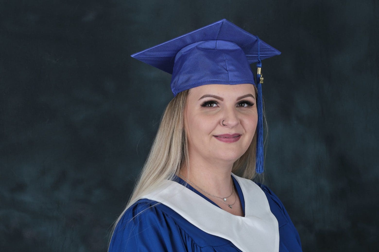 Oksana in her grad cap and gown smiling at the camera.