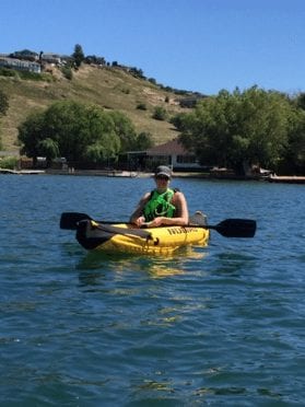 Lori kayaking between mountains. This is what makes her feel alive and brings her joy.